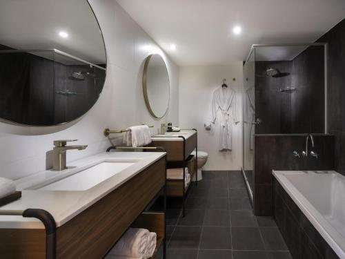 a bathroom with two sinks and a tub and a mirror at Mantra Terrace Brisbane in Brisbane