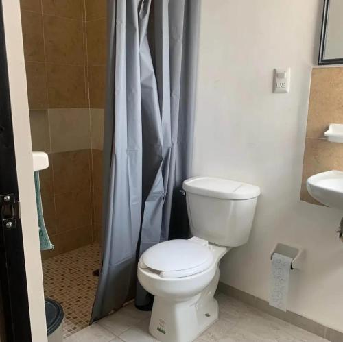 a bathroom with a toilet and a shower curtain at Excelente hogar para descansar in Gómez
