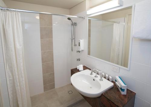a bathroom with a sink, mirror and bath tub at The Metropolitan Spring Hill in Brisbane