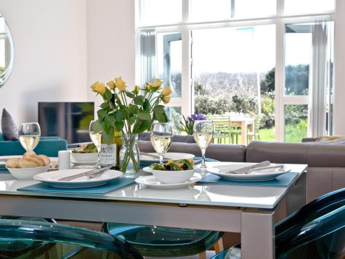 a dining room table with plates and wine glasses at Una Argentum 60 in Carbis Bay