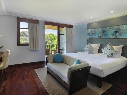 a bedroom with a large bed and a couch at Novotel Bali Nusa Dua in Nusa Dua
