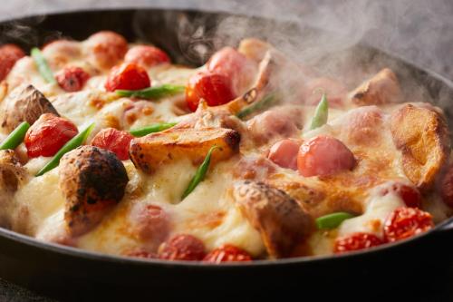 a close up of a pizza in a pan at Kamenoi Hotel Aso Park Resort in Aso