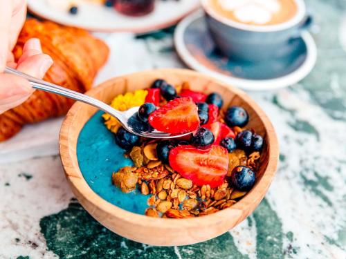 een kom ontbijtgranen en fruit met een lepel bij Hotel de L'Abbaye Le Tronchet - Handwritten Collection in Le Tronchet
