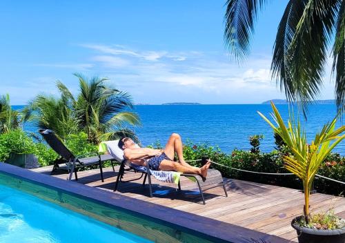 a man laying in lawn chairs next to a swimming pool at El Caribeo in Bocas Town
