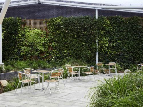 a patio with tables and chairs in a garden at Aparthotel Adagio London Brentford in Brentford