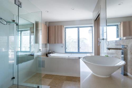 a bathroom with a tub and a shower and a sink at The Majestic Coolum Ocean Views & Poolside Escape in Coolum Beach