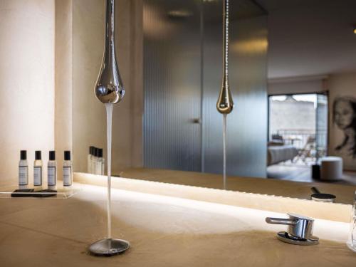a bathroom with two spoons on a sink with a mirror at Hotel & Spa Kasano Calvi - Handwritten Collection in Calvi