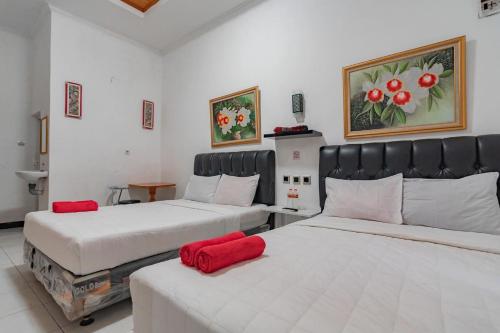 two beds in a room with red pillows on them at Wisma Vandera Syariah Garut Mitra RedDoorz in Garut