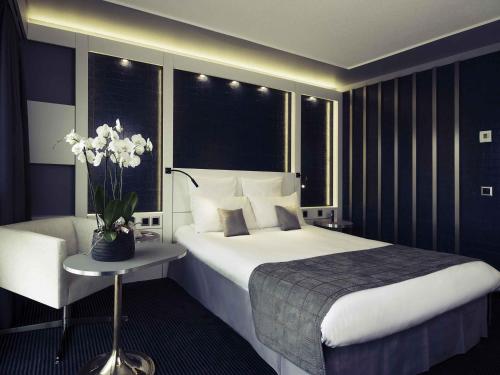a bedroom with a large bed and a table with flowers at Mercure Biel in Biel