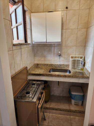 a small kitchen with a stove and a sink at Pousada Bartrô in Rio das Ostras