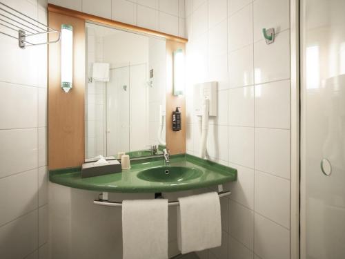 baño con lavabo verde y espejo en ibis Fribourg, en Fribourg