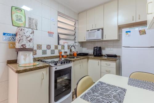 une cuisine avec des armoires blanches et un four à plaques de cuisson dans l'établissement Hospedaria da Mama 4 quartos Shopping e Metrô Santa Cruz, à São Paulo