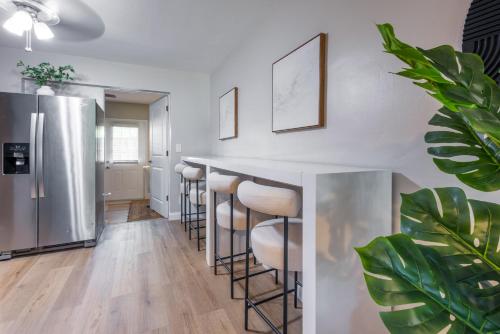 a kitchen with a bar with stools and a refrigerator at Biva Luxe in West Palm Beach