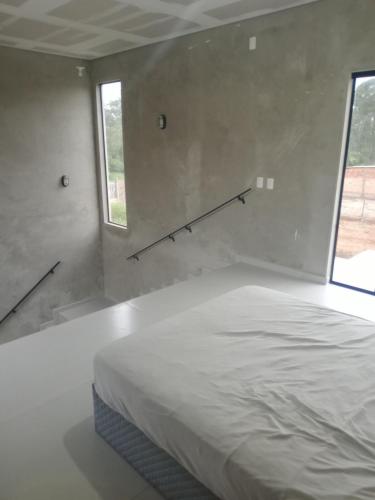 a white bed in a room with two windows at Casa Moderna com Wi-Fi e ar-condicionado in Itapoa
