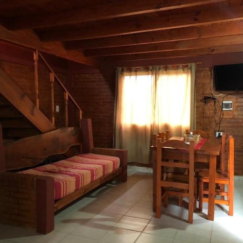 a bedroom with a bed and a table and a window at Cabañas Gemas del Lago in Potrero de los Funes