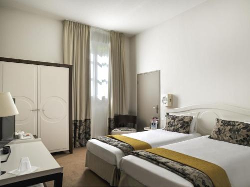 una camera d'albergo con due letti e una finestra di Mercure Rambouillet Relays Du Château a Rambouillet