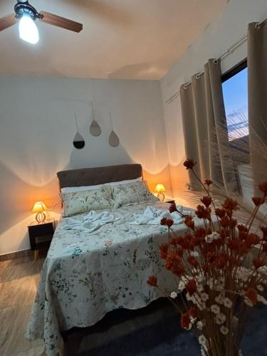a bedroom with a bed and a window and flowers at Tríade Chalé da Canastra 1 in São Roque de Minas