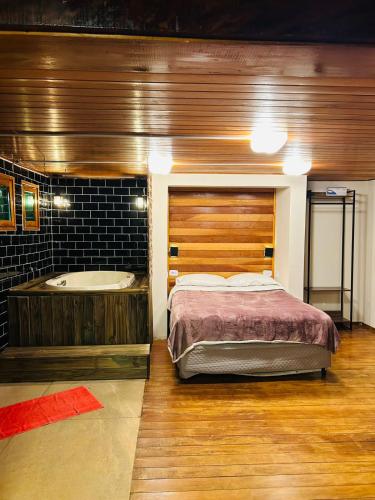 a bedroom with a bed and a bath tub at Pousada Brisa da Montanha in Campos do Jordão