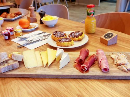 uma mesa de madeira com queijo, linguiça e outros alimentos em Novotel Montpellier em Montpellier