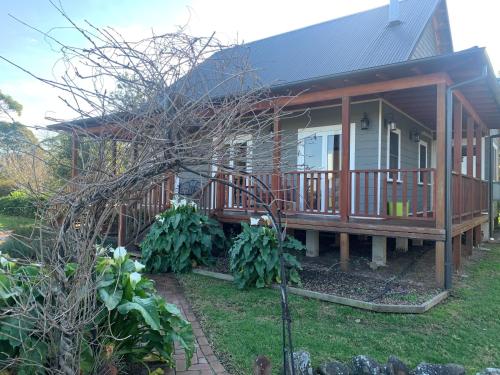 a house with a large deck with a porch at Peppergrove Cottage in Berry