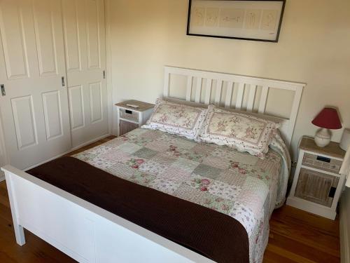 a bedroom with a large white bed with flowers on it at Peppergrove Cottage in Berry