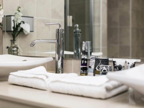 a bathroom with a sink and a mirror and towels at Mercure Haydock Hotel in Haydock