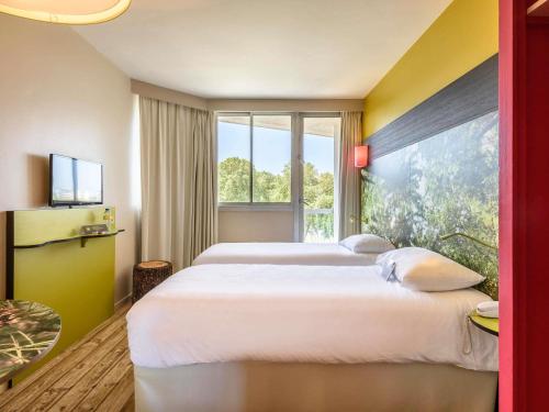 a hotel room with two beds and a large window at ibis styles Dax Centre in Dax