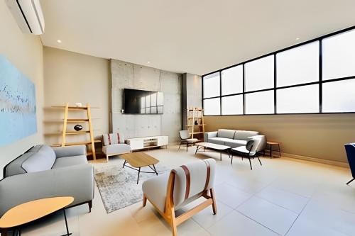 a large living room with couches and chairs at Luxury aprt in front of Fundidora Park, gym, BBQ. in Monterrey