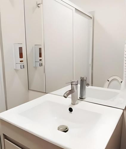 a white bathroom with a sink and a mirror at Luxury aprt in front of Fundidora Park, gym, BBQ. in Monterrey