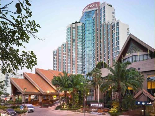 a large building with palm trees in front of a street at Pullman Khon Kaen Raja Orchid in Khon Kaen