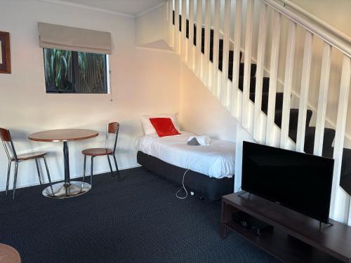 a room with a bed and a table with a tv at Ascot Motor Lodge in Wellington
