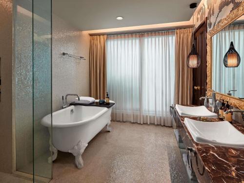 a bathroom with two sinks and a bath tub at Hotel de l'Opera Hanoi - MGallery in Hanoi