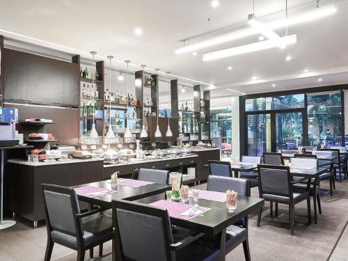 a restaurant with tables and chairs and a bar at Novotel Abidjan Plateau in Abidjan