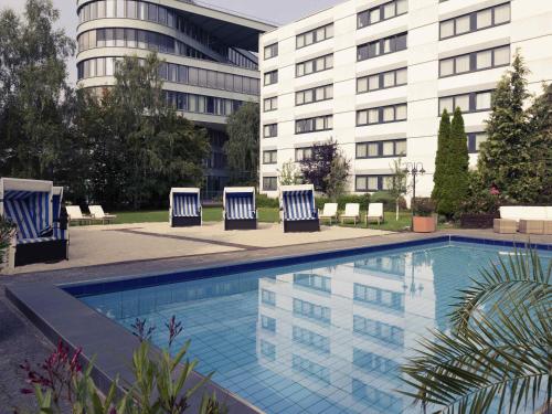 a pool with lounge chairs and a building at Mercure Hotel Frankfurt Eschborn Ost in Eschborn