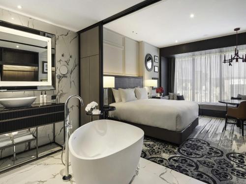 a bedroom with a bed and a bath tub and a bathroom at Sofitel Adelaide in Adelaide