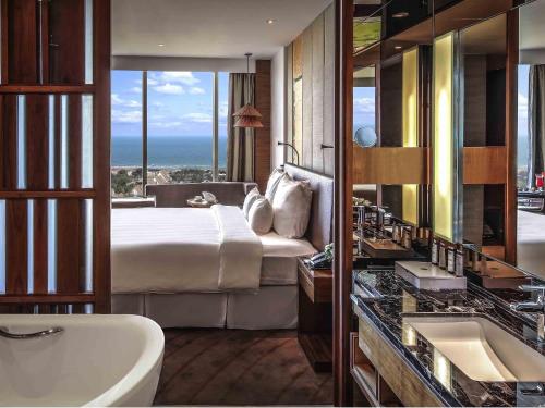 a bedroom with a bed and a bathroom with a sink at Pullman Vung Tau in Vung Tau