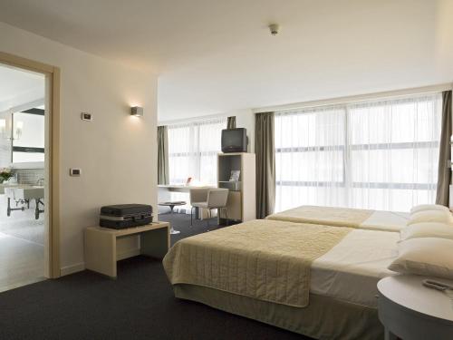 a hotel room with a large bed and a desk at Mercure Palermo Centro in Palermo