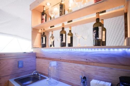 a bunch of wine bottles on a shelf above a sink at Wine Country Dome Getaway 1 in El Junco