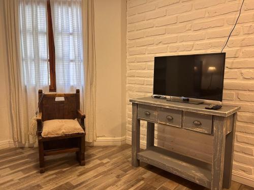 Una sala de estar con un televisor sobre una cómoda con una silla. en CosmoSur - El Bolson Centro, en El Bolsón