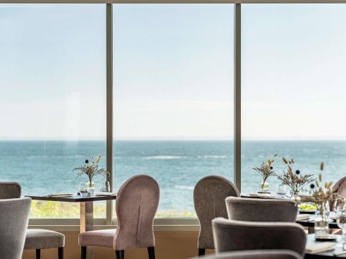 a restaurant with tables and chairs and a view of the ocean at Sofitel Quiberon Thalassa sea & spa in Quiberon