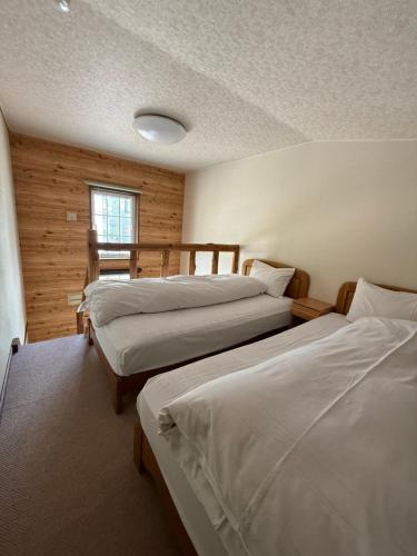 Un dormitorio con tres camas y una ventana. en Pension New White Bear, en Kutchan