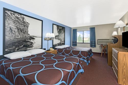 a hotel room with two beds and a television at Super 8 by Wyndham Wisconsin Dells in Wisconsin Dells