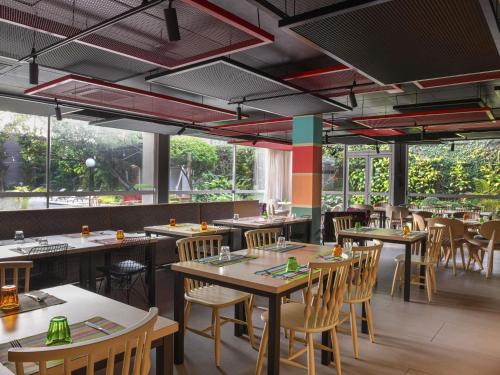 a restaurant with tables and chairs and large windows at Ibis Styles Abidjan Marcory in Abidjan