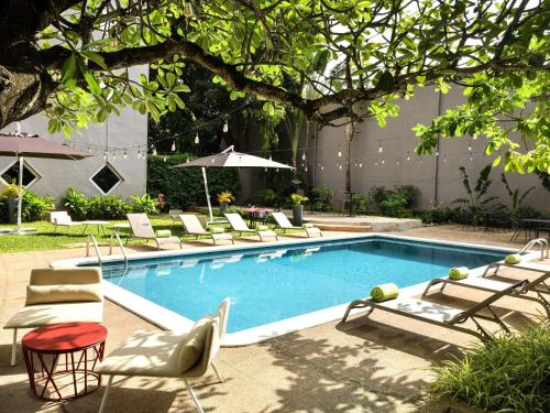 a swimming pool with lounge chairs and an umbrella at Ibis Styles Abidjan Marcory in Abidjan