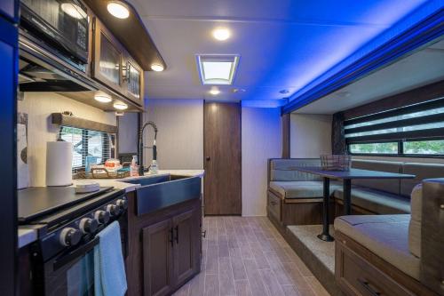 an rv kitchen with a sink and a table at The Backyard Glampground - Camper Fire Pit & Games in Tampa