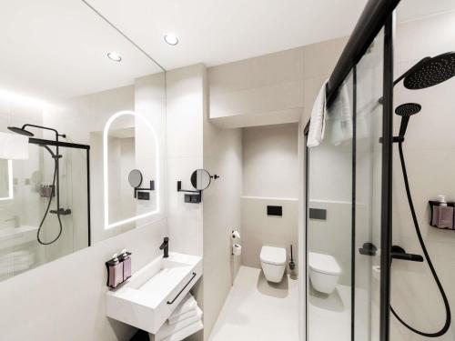 a white bathroom with a shower and a sink at TRIBE Riga City Centre in Rīga