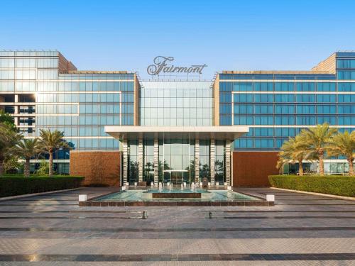 a large glass building with a fountain in front of it at Fairmont Bab Al Bahr in Abu Dhabi