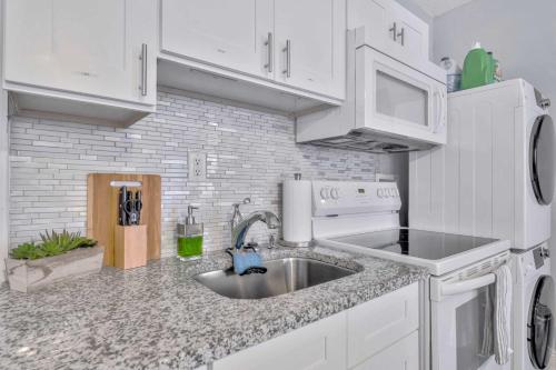 a kitchen with white cabinets and a sink at Sunny Tampa Home Near Downtown & Stadiums in Tampa