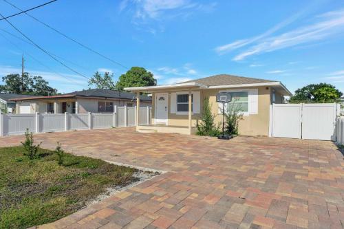 a house with a white fence and a brick driveway at Sunny Tampa Home Near Downtown & Stadiums in Tampa