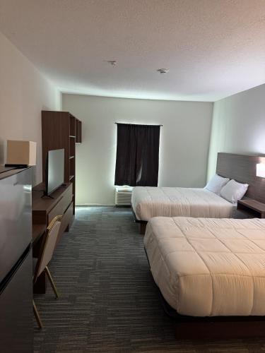 a hotel room with two beds and a television at Hotel de Luxe Extended Stay in Sulphur